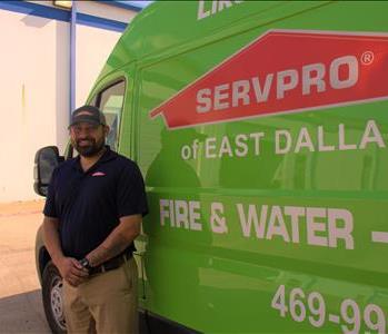 Male employee, Steven Production Manager smiling with SERVPRO green van.