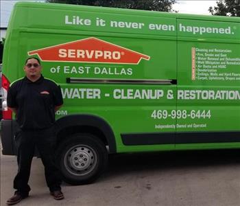 Male employee Jesus standing next to SERVPRO green truck